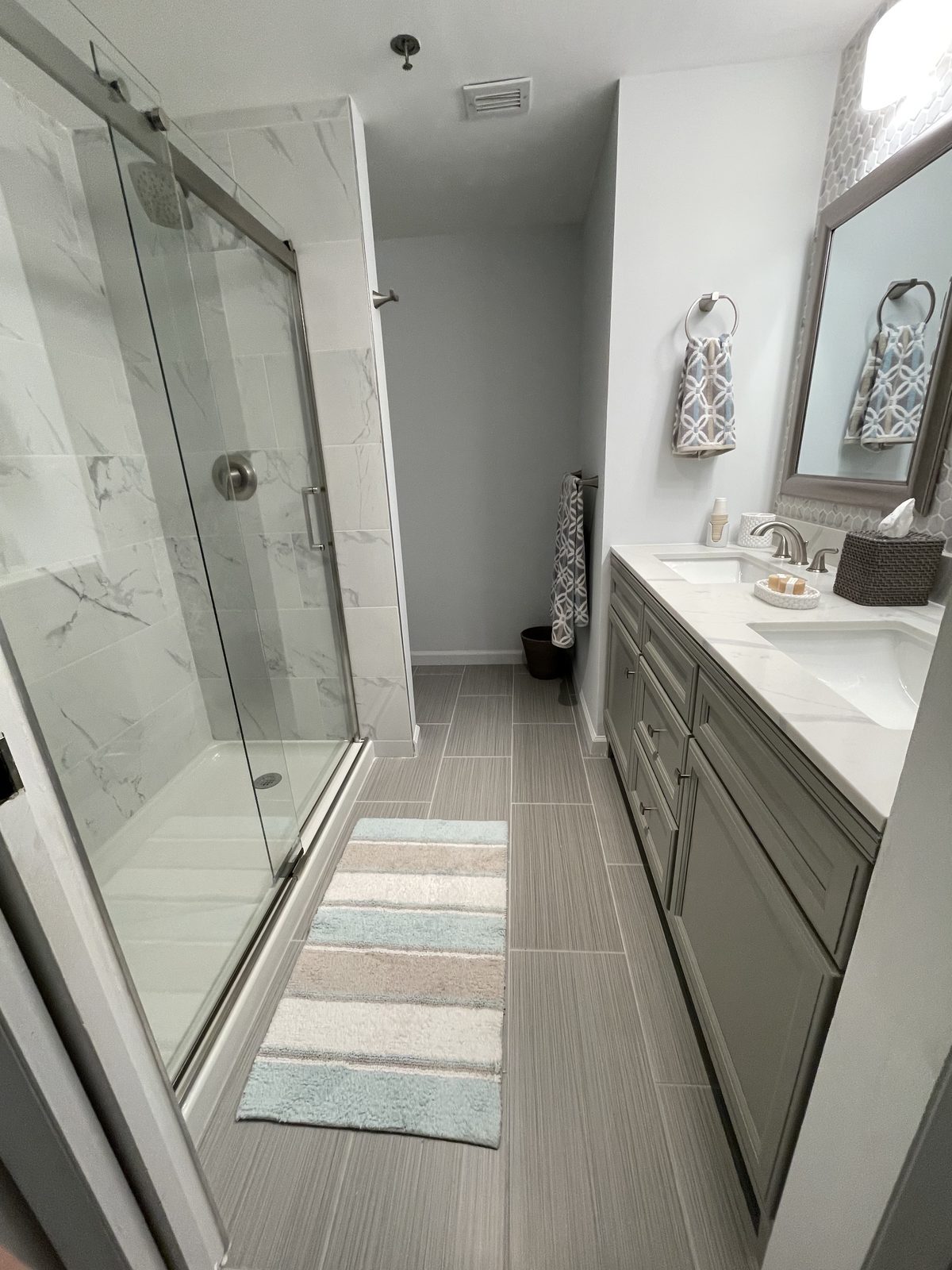 Glass shower door with marble-look tile and wood-look floor, remodeled by Boardwalk Renovations