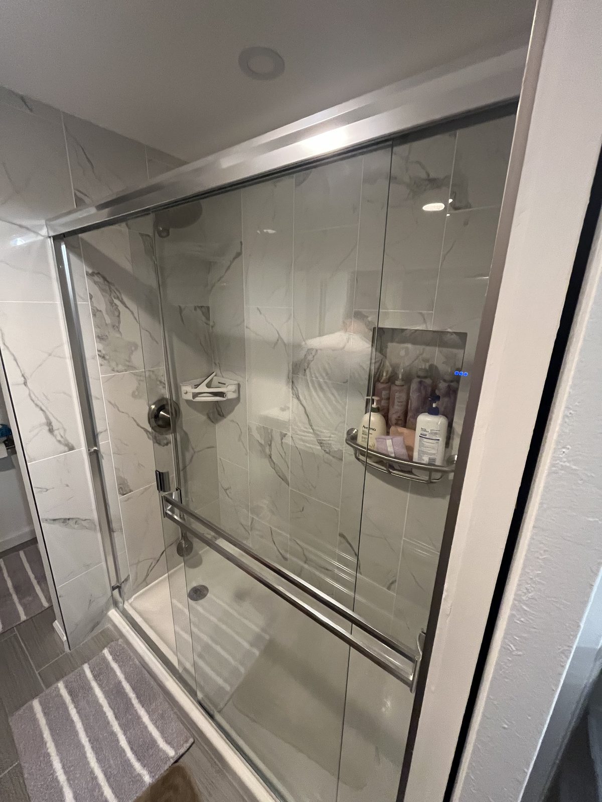 Tub with sliding glass doors, marble-look tile and built-in niche, remodeled by Boardwalk Renovations