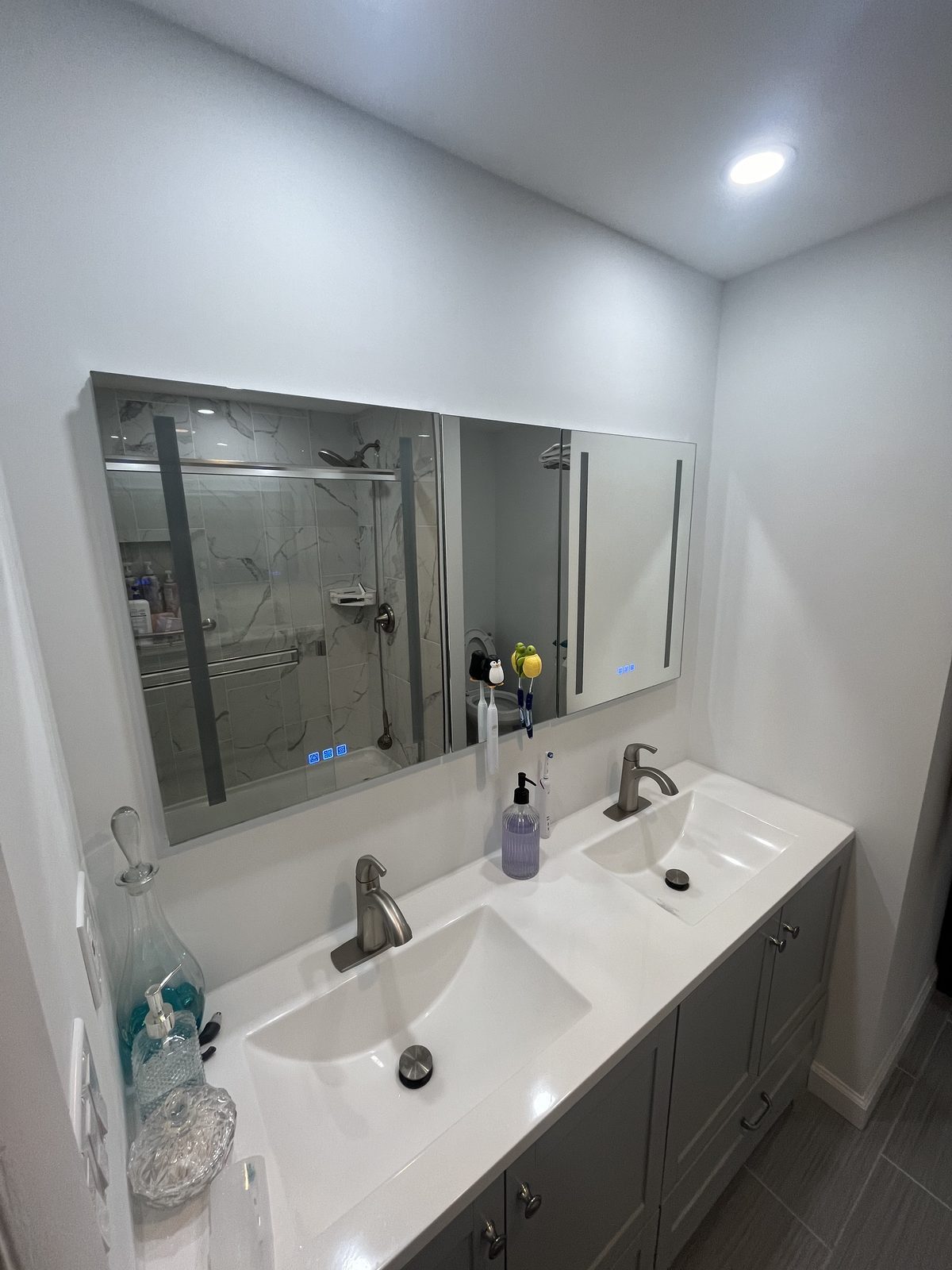 Gray double vanity with white top and lighted mirror, remodeled by Boardwalk Renovations
