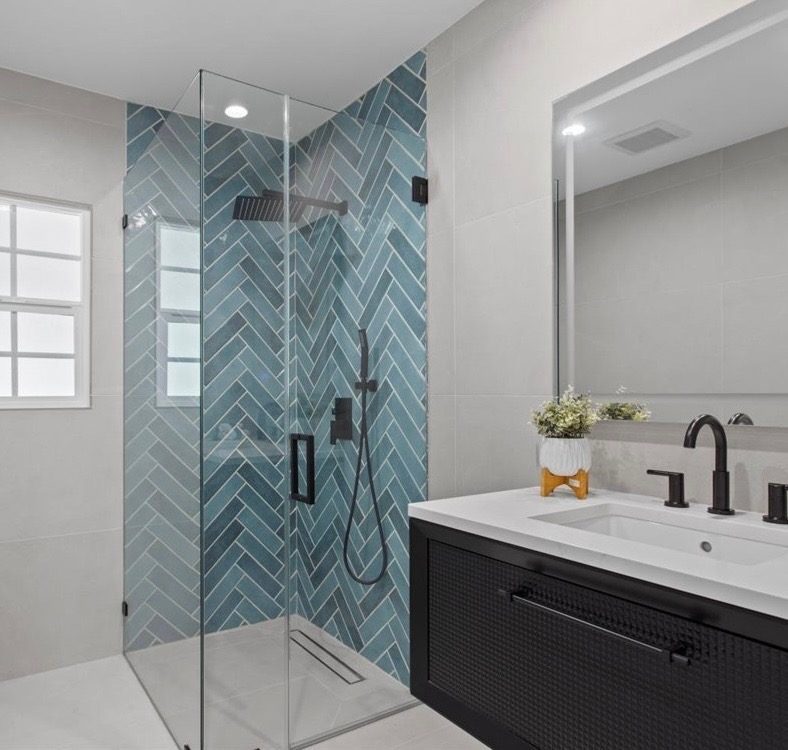 Teal herringbone tile walk-in shower with frameless glass and black fixtures, remodeled by Boardwalk Renovations