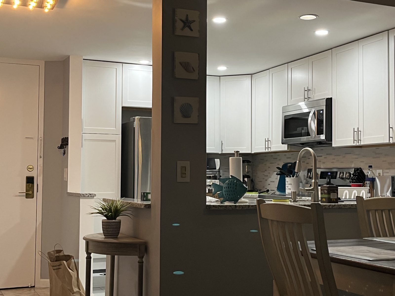 White shaker kitchen with stainless microwave and granite counters, remodeled by Boardwalk Renovations