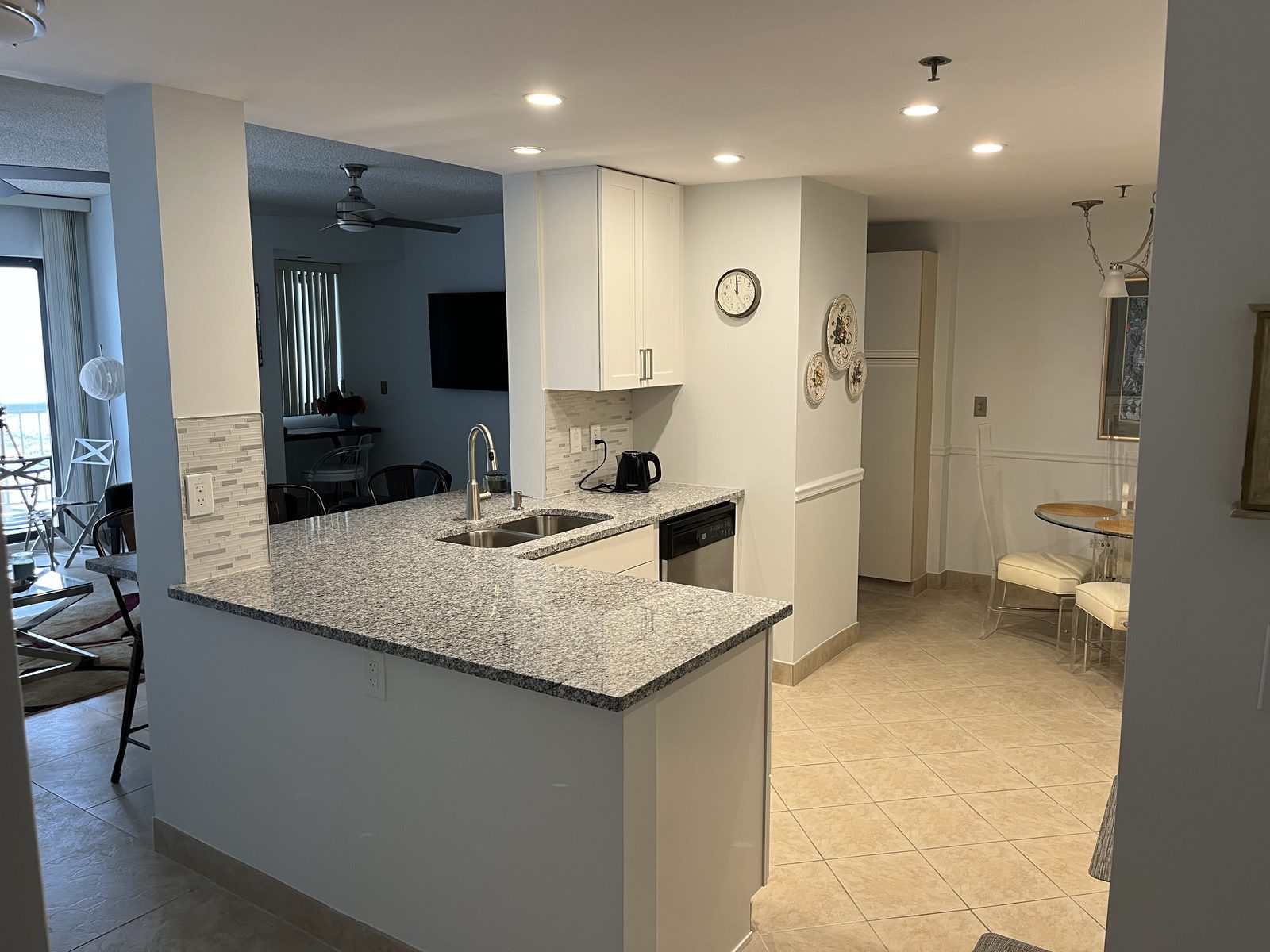 Granite peninsula with white cabinets opening to the living room, remodeled by Boardwalk Renovations