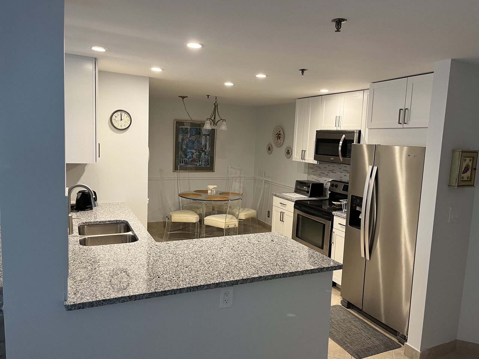 Granite peninsula kitchen with stainless appliances and dining area, remodeled by Boardwalk Renovations
