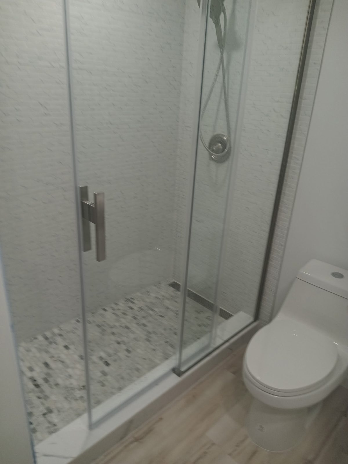 Glass sliding-door shower with pebble tile floor, remodeled by Boardwalk Renovations