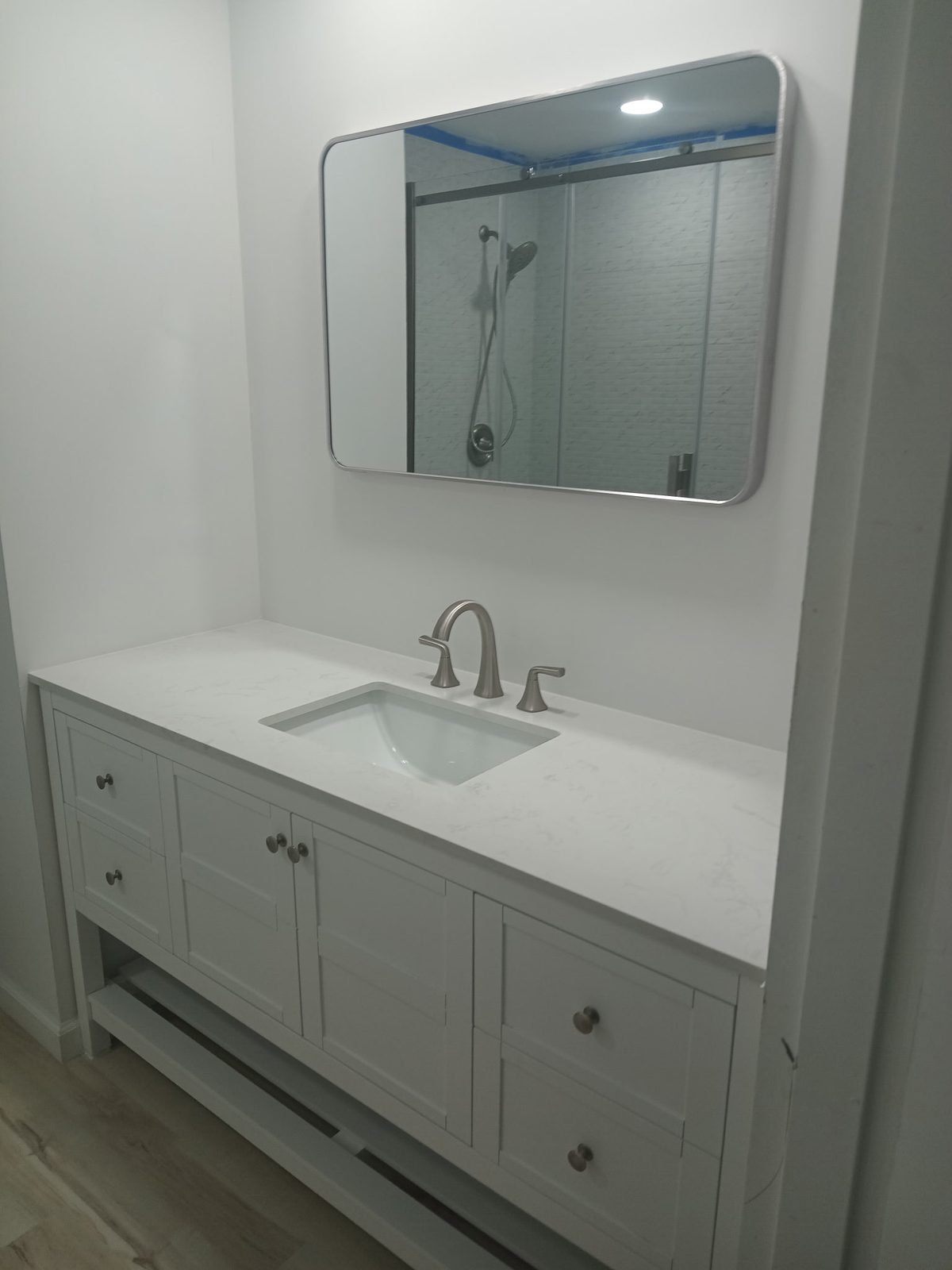 White vanity with quartz top and rounded mirror, remodeled by Boardwalk Renovations