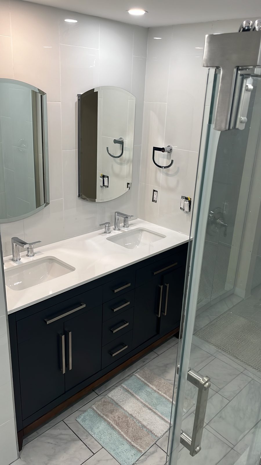 Navy double vanity with white quartz top and rounded mirrors, remodeled by Boardwalk Renovations