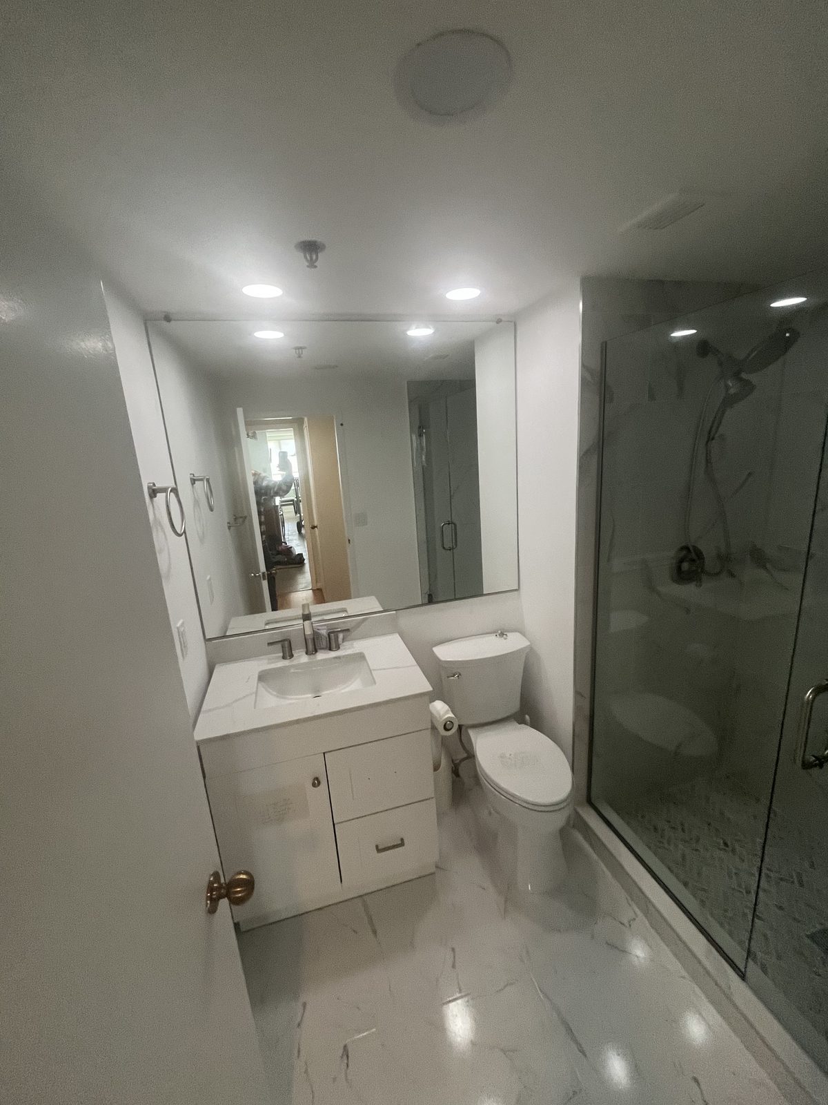 Bathroom with white vanity, marble-look tile and glass shower, remodeled by Boardwalk Renovations