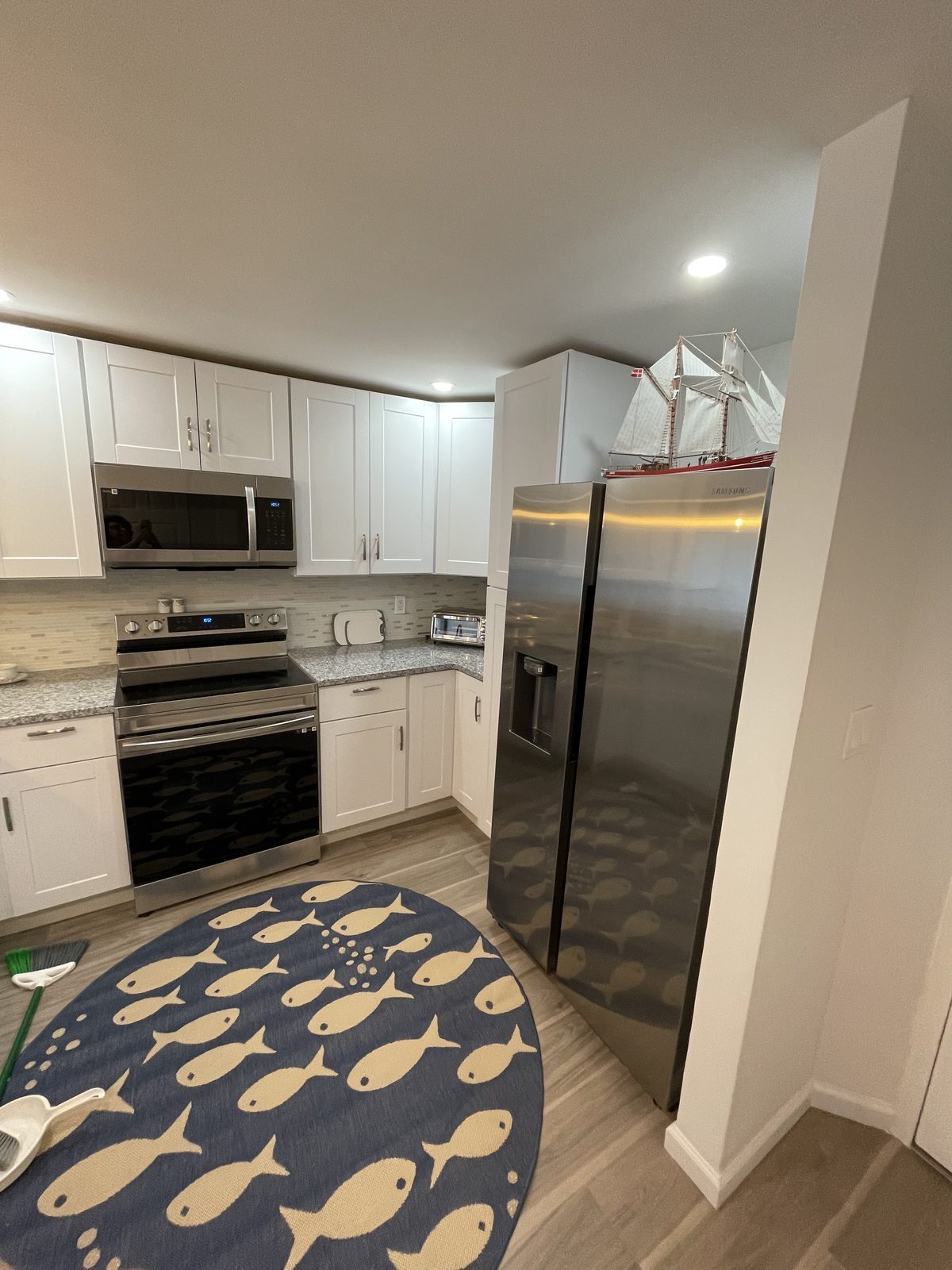 White cabinets with stainless refrigerator, range and microwave, remodeled by Boardwalk Renovations