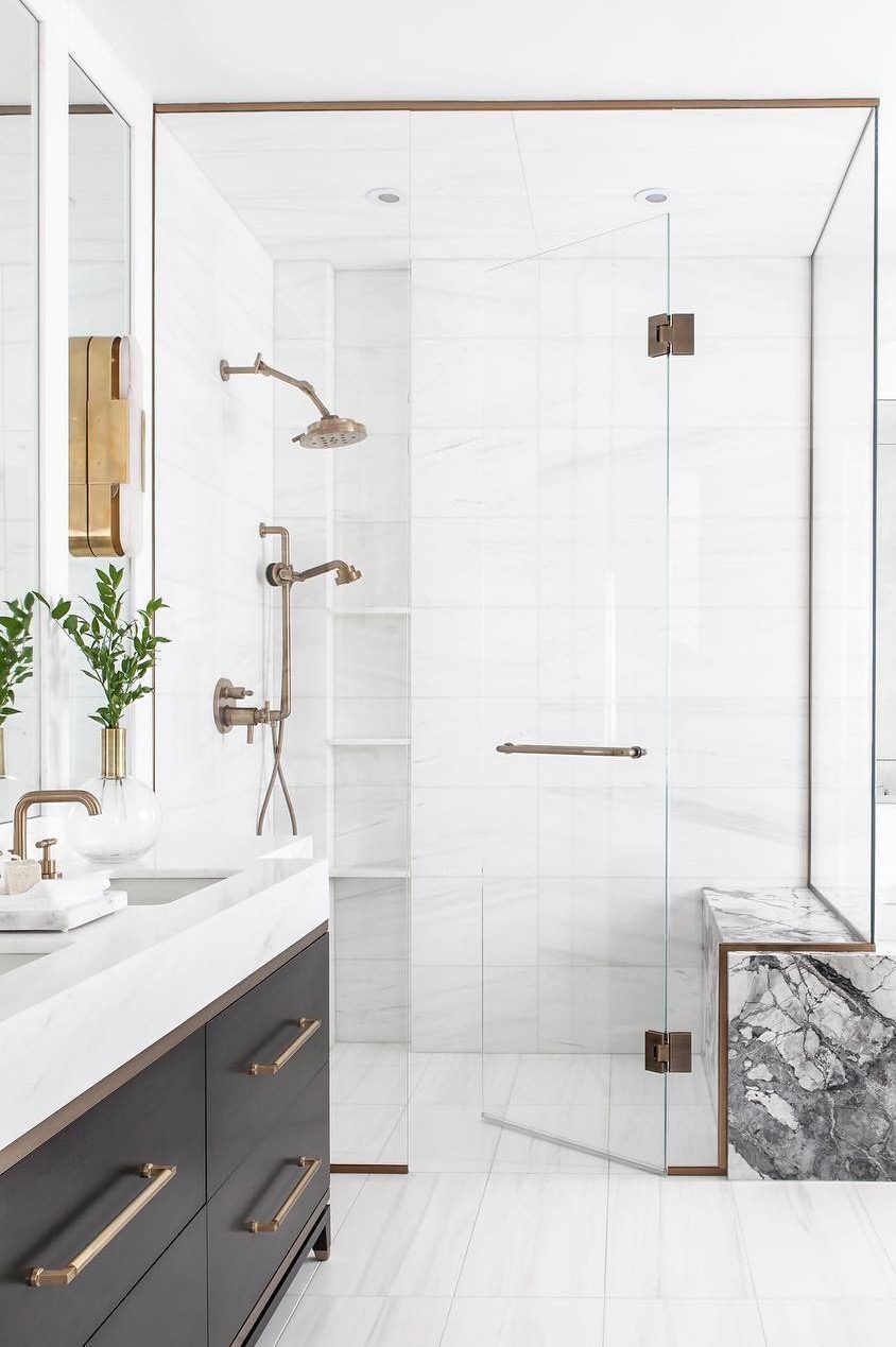 Frameless glass walk-in shower with white tile and brass fixtures, remodeled by Boardwalk Renovations