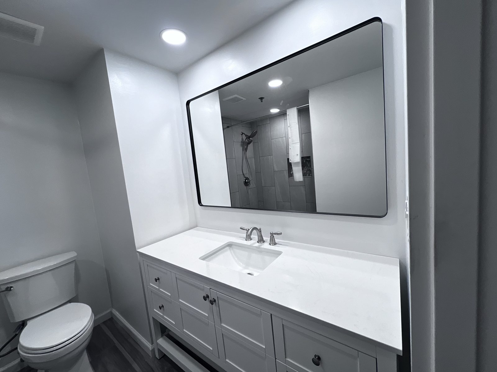 Gray vanity with white quartz top and black-framed mirror, remodeled by Boardwalk Renovations