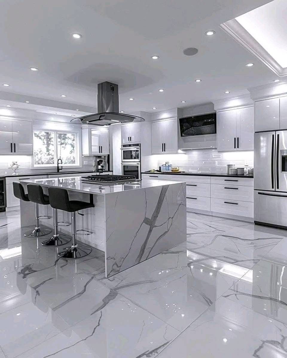 Kitchen island with white quartz waterfall edge, black pendant lights and marble-look floor tile, remodeled by Boardwalk Renovations