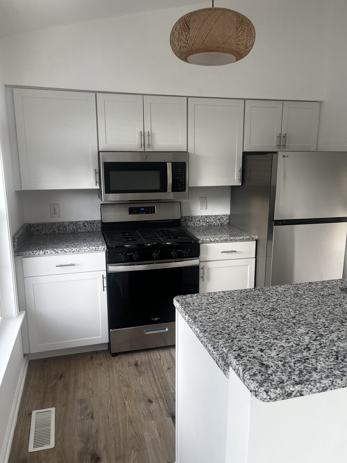 White shaker cabinets with gray granite countertops and stainless gas range, remodeled by Boardwalk Renovations